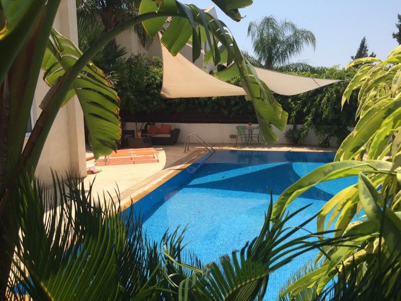 Panorama Luxury Villa's private pool framed by palm and banana leaves under a shade sail