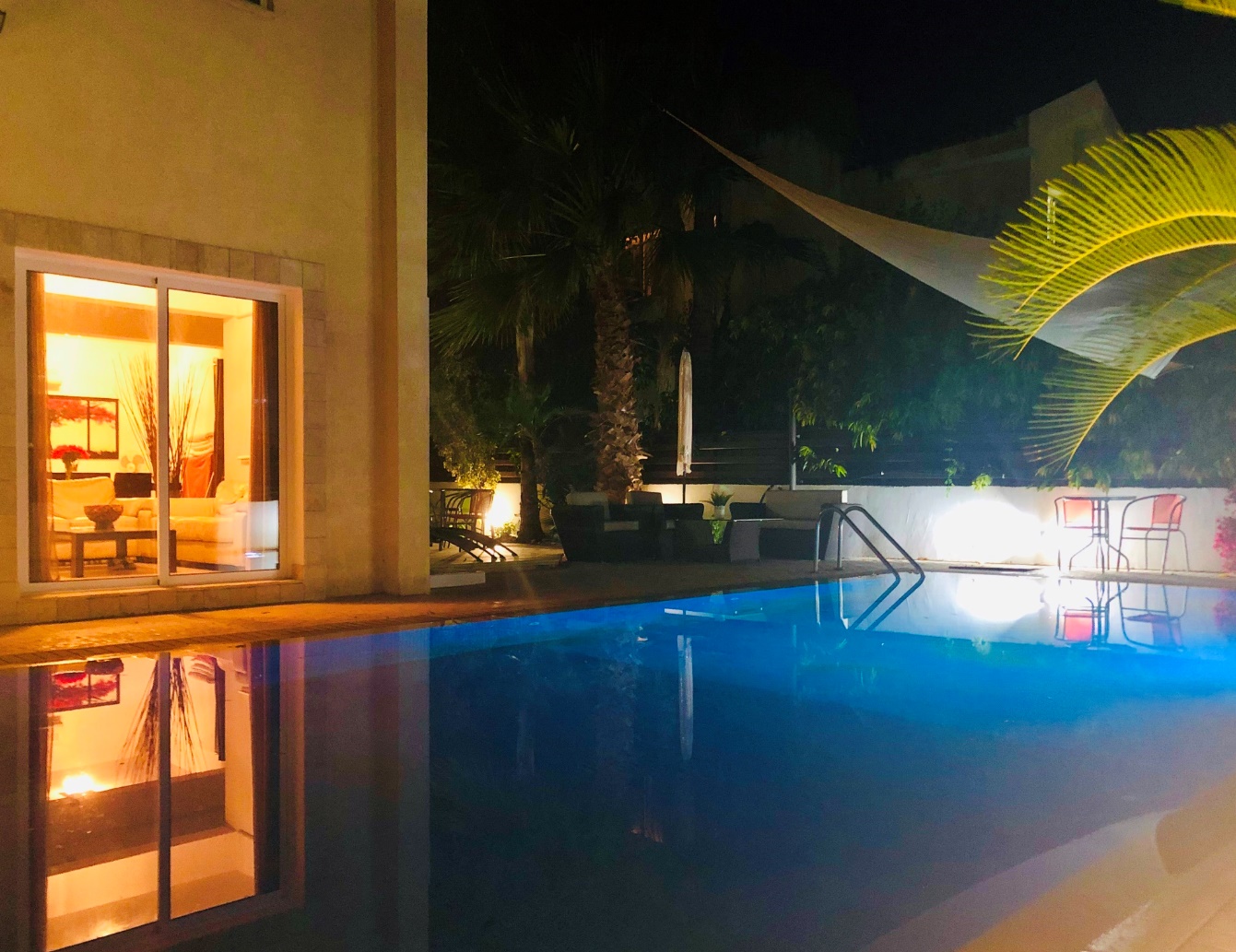 Panorama Luxury Villa pool illuminated at night with warm interior light spilling onto the terrace